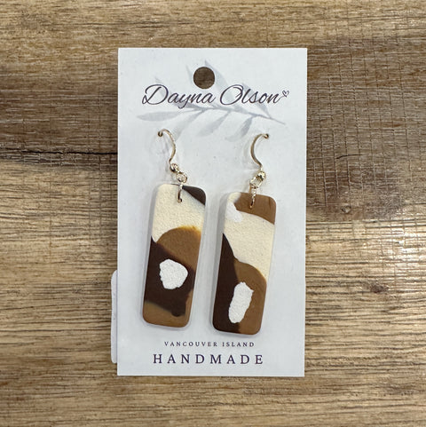 Pair of earrings on a 'Dayna Olson' card with a wooden background