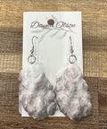 Marble-textured earrings on a branded card against a wooden background
