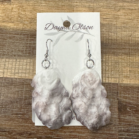 Marble-textured earrings on a branded card against a wooden background