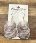 Oyster shell earrings on a branded card with a wooden background
