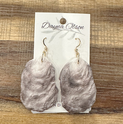 Oyster shell earrings on a branded card with a wooden background