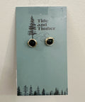 Pair of black stud earrings on a 'Tide and Timber' branded card with a forest design.