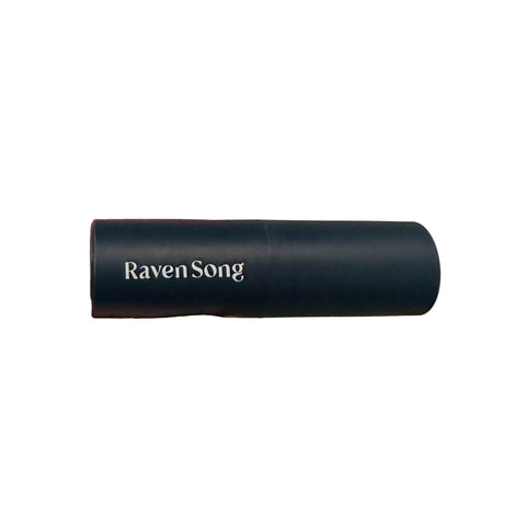 Hand holding a cylindrical product labeled 'Raven Song' against a neutral background