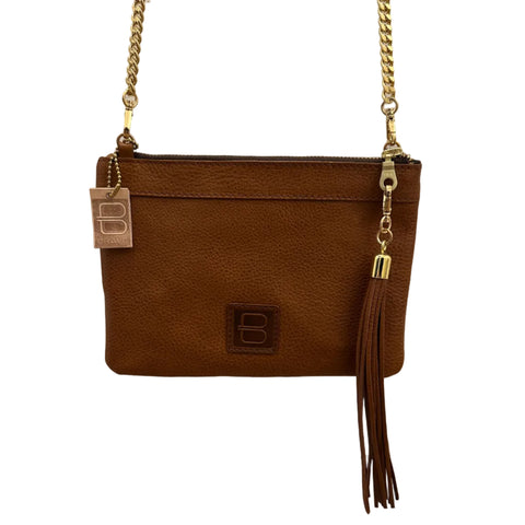 Brown leather clutch with gold chain strap on a light wooden background