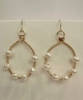 Gold hoop earrings with pearl beads on a white background