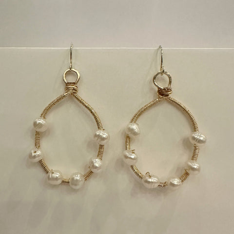 Gold hoop earrings with pearl beads on a white background