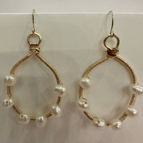 Gold hoop earrings with pearl beads on a white background