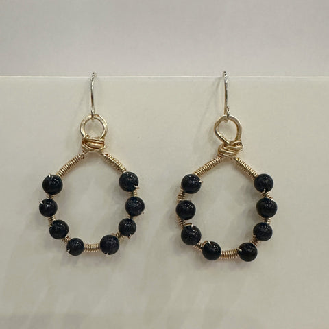 Pair of hoop earrings with black beads on a light background