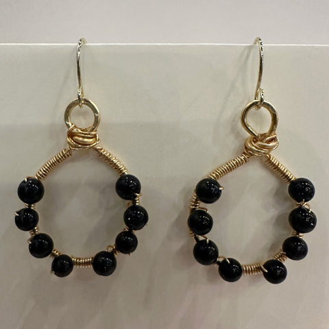 Pair of hoop earrings with black beads and gold wire on a white background