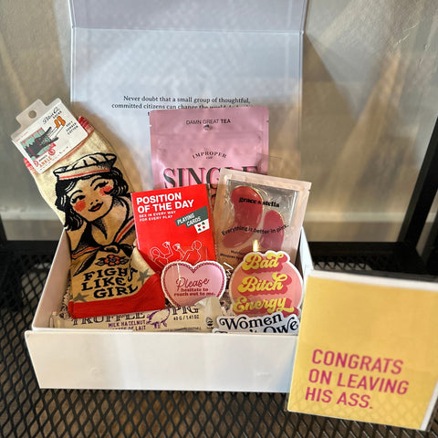 Box with various items including a card and snacks on a metal surface.