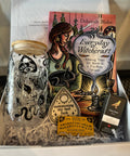 Box containing a glass jar with black designs, a book titled 'Everyday Witchcraft', and other items.