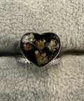 Heart-shaped ring with floral design on a textured gray surface