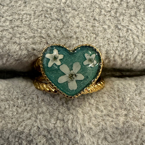 Heart-shaped ring with floral design on a textured surface