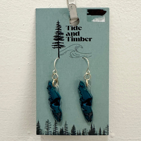 Blue leaf-shaped earrings on a Tide and Timber branded card, clipped to a light wooden surface.