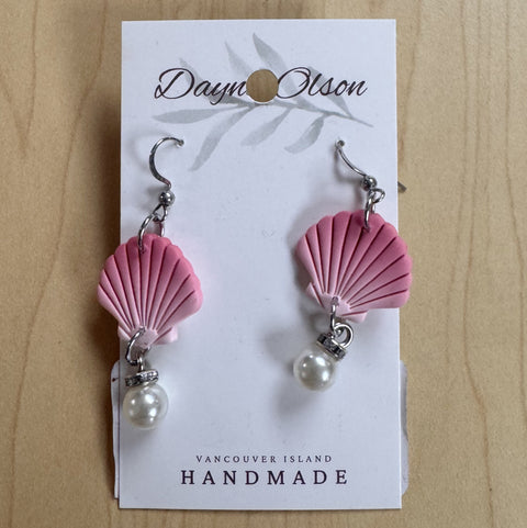Pink shell earrings with pearl drops on a 'Dayn Olson' card against a wooden background
