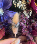 Butterfly decorative pin held over a bouquet of flowers