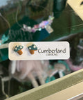 Mushroom-shaped earrings on a 'Cumberland Creations' card with a blurred background
