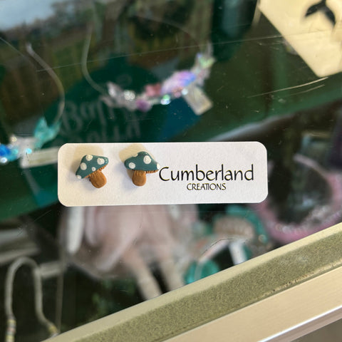 Mushroom-shaped earrings on a 'Cumberland Creations' card with a blurred background