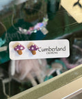 Two mushroom-shaped earrings on a 'Cumberland' branded card, with a blurred background.