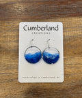 Blue earrings on a Cumberland Creations card against a wooden background