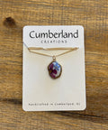 Necklace with a pendant on a Cumberland Creations card against a wooden background