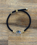 Black hair tie with gold accents on a wooden surface