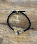 Black hair tie with gold clasp on a wooden surface