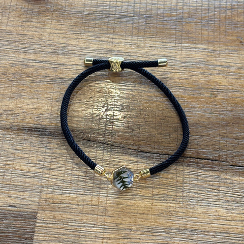 Black hair tie with gold clasp on a wooden surface
