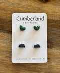 Three pairs of earrings on a 'Cumberland Creations' card on a wooden surface
