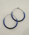 Pair of hoop earrings with blue and black beaded accents on a light gray background