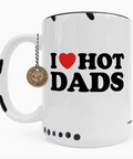 A white ceramic coffee mug with black polka dots, featuring the text 'I [red heart] HOT DADS' in black. A small round bronze-colored 'Crazy Dog Coffee Company' hanging charm is attached to the handle by a black-and-white string.