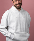 A smiling man with glasses and a beard wearing a light gray heather hoodie with the text 'I DON'T HAVE THE ENERGY FOR YOU TO TRY' printed on the chest, posed against a solid dusty pink background.