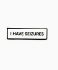 Black rectangular sign with 'I HAVE SEIZURES' text on a white background