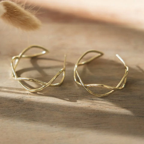 Gold earrings on a wooden surface