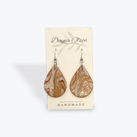 Teardrop-shaped earrings on a 'Dayna Otson' card with a beige background