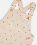Close-up of the floral corduroy fabric, strap buckles and buttons on the Deux par Deux overall dress.