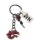Keychain with floral charm and 'JUN' tag on a textured surface