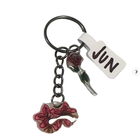 Keychain with floral charm and 'JUN' tag on a textured surface