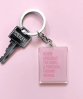 An acrylic keychain with a square tag featuring text in pink, attached to a metal keyring and a key.