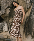 Woman in a floral dress standing among rocky cliffs