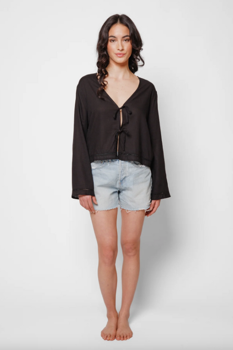 Woman wearing a black blouse and denim shorts on a white background