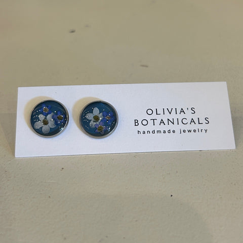 Pair of blue floral earrings on a white card with 'Olivia's Botanicals' branding, against a beige background.