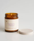 Candle in a glass jar labeled 'Lavender Unwind' on a light background