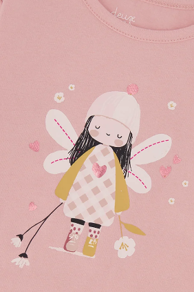 A close-up of a pink long-sleeve children's top featuring a cute fairy graphic on the front. The graphic depicts a girl fairy with black hair, a pink and white checkered dress, a yellow cape, and pink wings, surrounded by small white flowers and pink hearts.