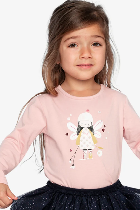 A young girl wearing a light pink long-sleeve t-shirt with a cartoon fairy graphic on the front, paired with a navy blue polka-dot tutu skirt, set against a plain light gray background.