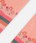 A close-up of a pink knit textile strip with a floral pattern and horizontal striped bands, shown diagonally on a light gray background.