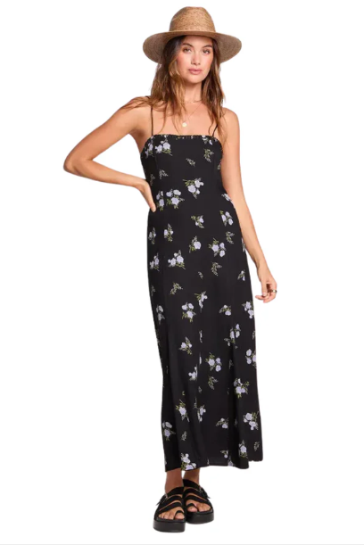 Woman wearing a black floral dress and straw hat on a white background