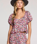 Woman wearing a floral dress and hat against a plain background