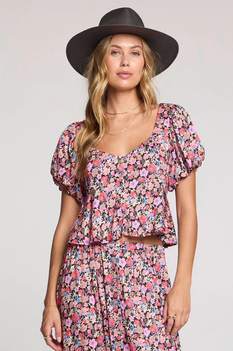 Woman wearing a floral dress and hat against a plain background