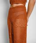 Brown crochet top and pants on a neutral background